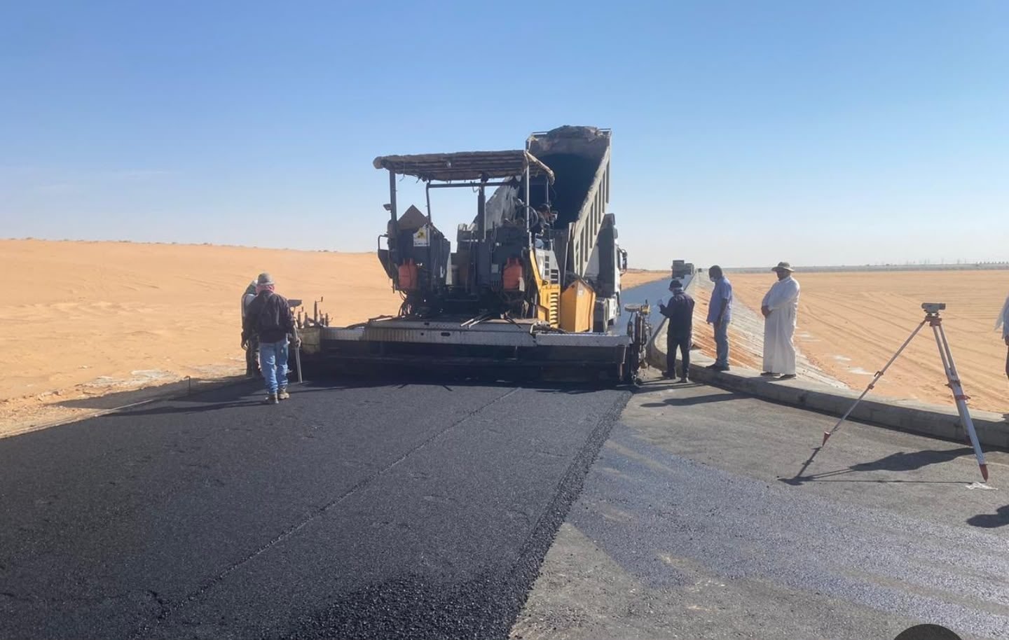 فرادة أسفلت وفريق زفلتة أثناء تنفيذ طريق في الصحراء